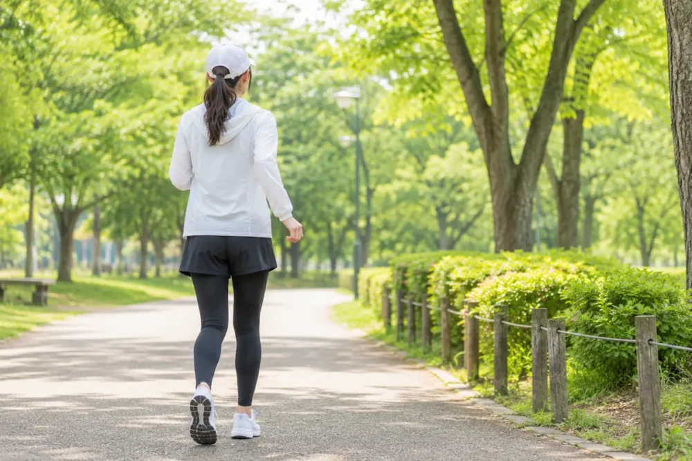 公園をウォーキングする女性の後ろ姿